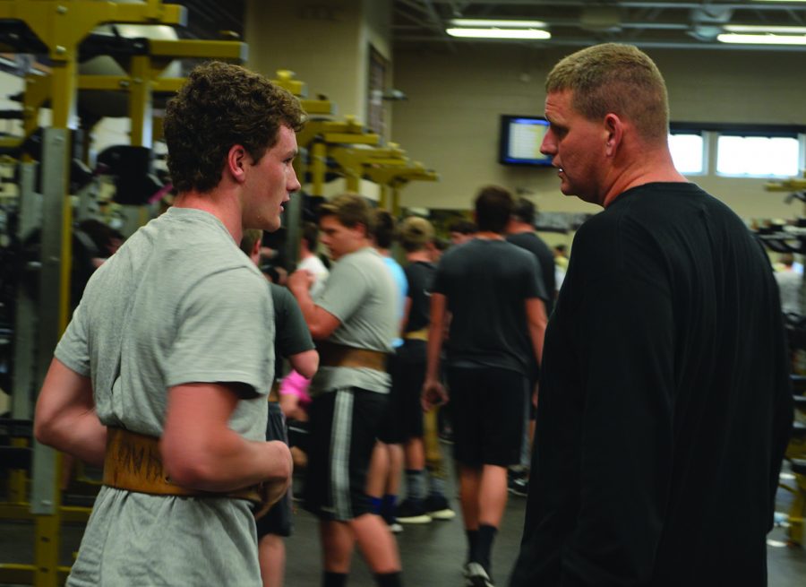 Head coach Jason Simmons talks to junior Ashton Mills after Mills completes a max out squat. NHS football players have weights Mondays and Wednesdays. 