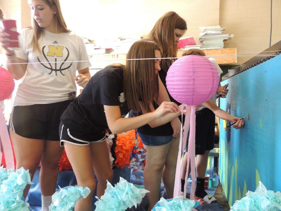 Freshmen Katelyn Kinyon, Anna Sullivan, and Arden Woodall work hard on the freshmen homecoming float. Despite the flooding, the parade is still scheduled for Friday afternoon.