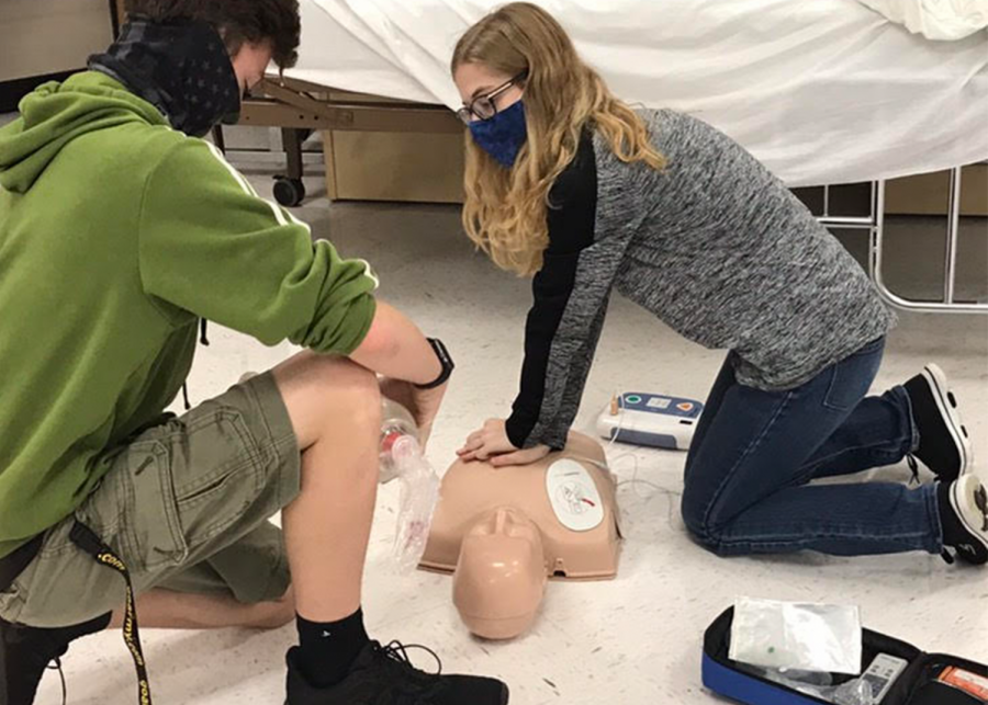 Junior Porter Scott and senior Lilli Howell work on CPR dummy.