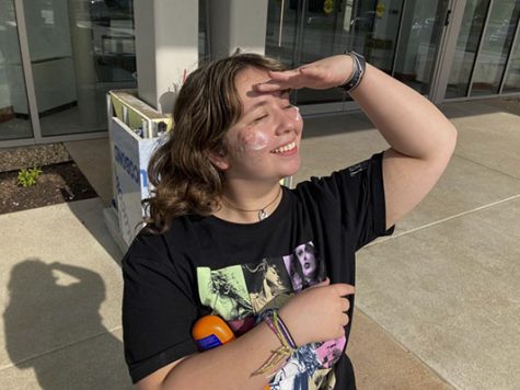 Sophomore Claire Bergdoll poses in front of the sun with sunscreen applied on her cheeks. Athough she thinks that putting sunscreen on can be a hassle, she still chooses to wear it in spring and summer to help protect her skin from skin cancer, aging, and sunburn.
