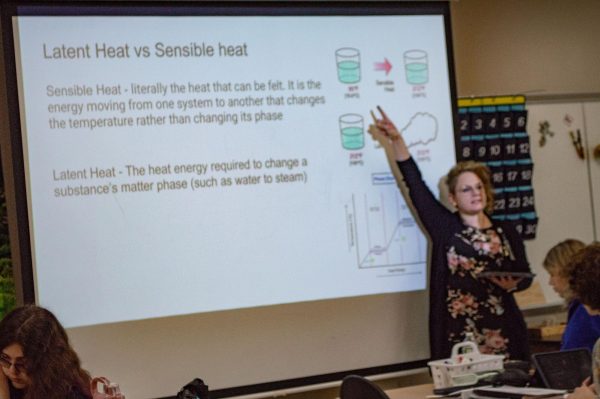 Meteorology teacher Skylee Shaffer stands in front of her class teaching a lesson. They are pointing out the differences between sensible and latent heat.