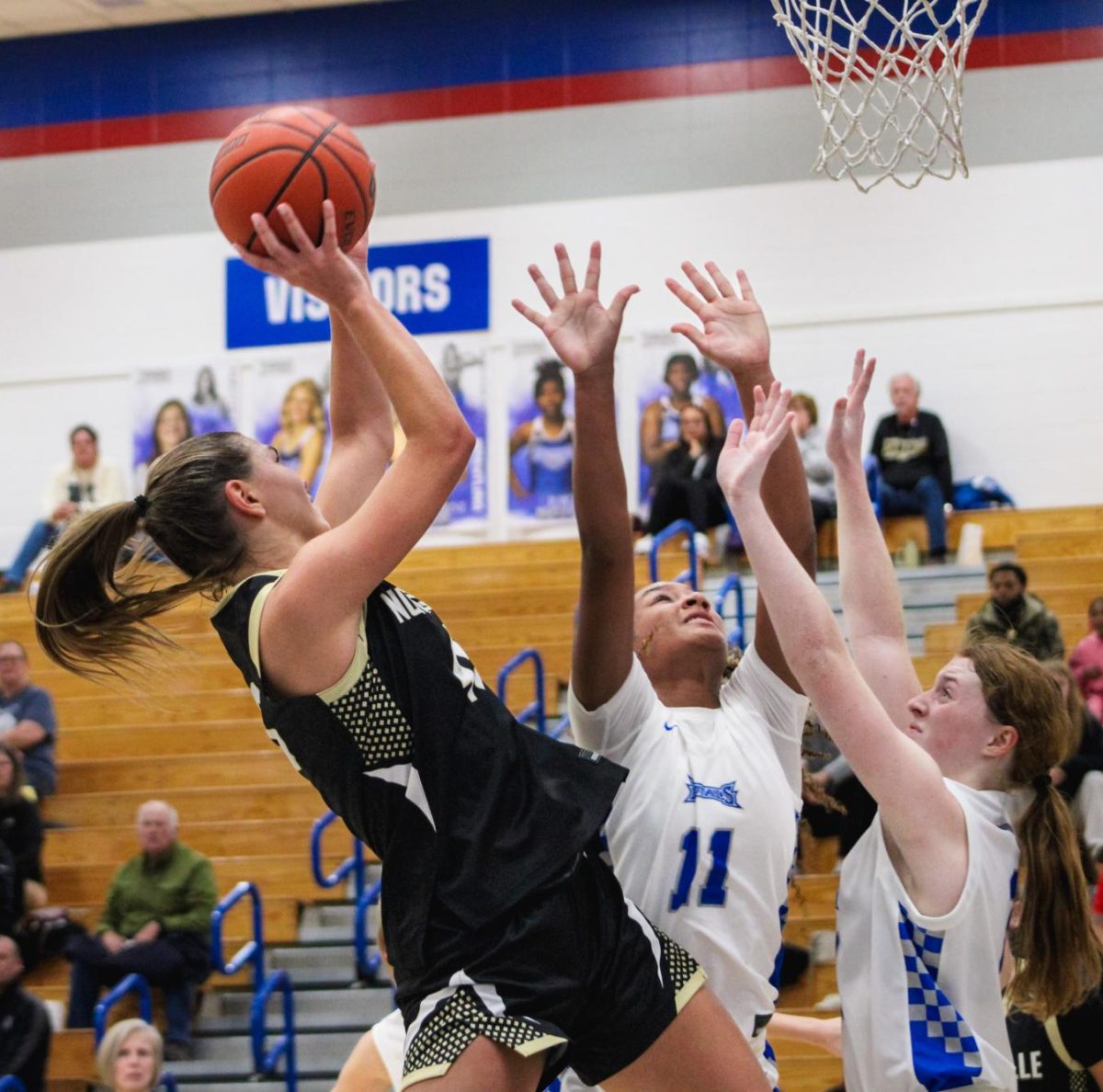 Miller basketball star CC Quigley shoots a basket against the HSE Royals. Despite the Miller girls' strong athletic performance, the stands behind them are nearly empty.