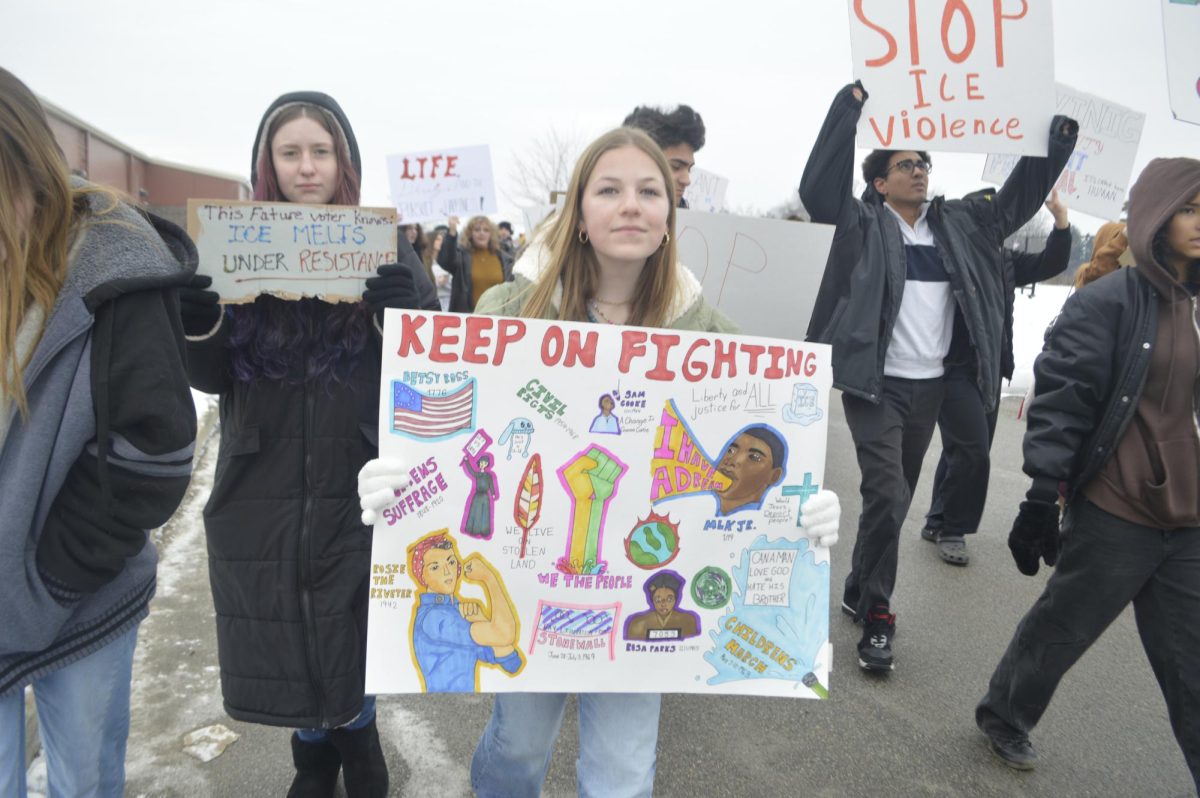 Student Piper Creager walks on the march route behind NHS with a homemade sign. She hopes that her presence leads to change in the country and community. 
