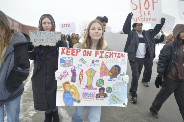 Student Piper Creager walks on the march route behind NHS with a homemade sign. She hopes that her presence leads to change in the country and community. 